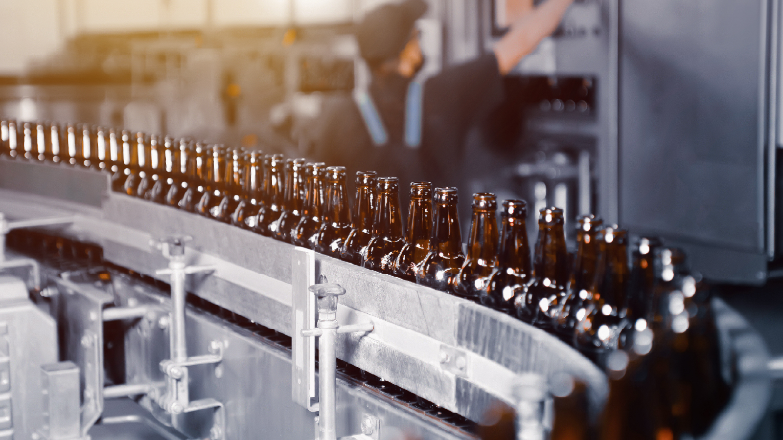 Image of dozens of bottles crowded on a conveyor belt
