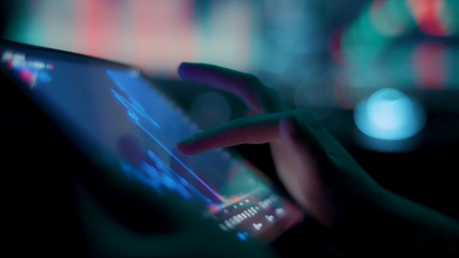 A close-up of a hand interacting with a touchscreen displaying financial or analytical data, with a blurred, colorful background.