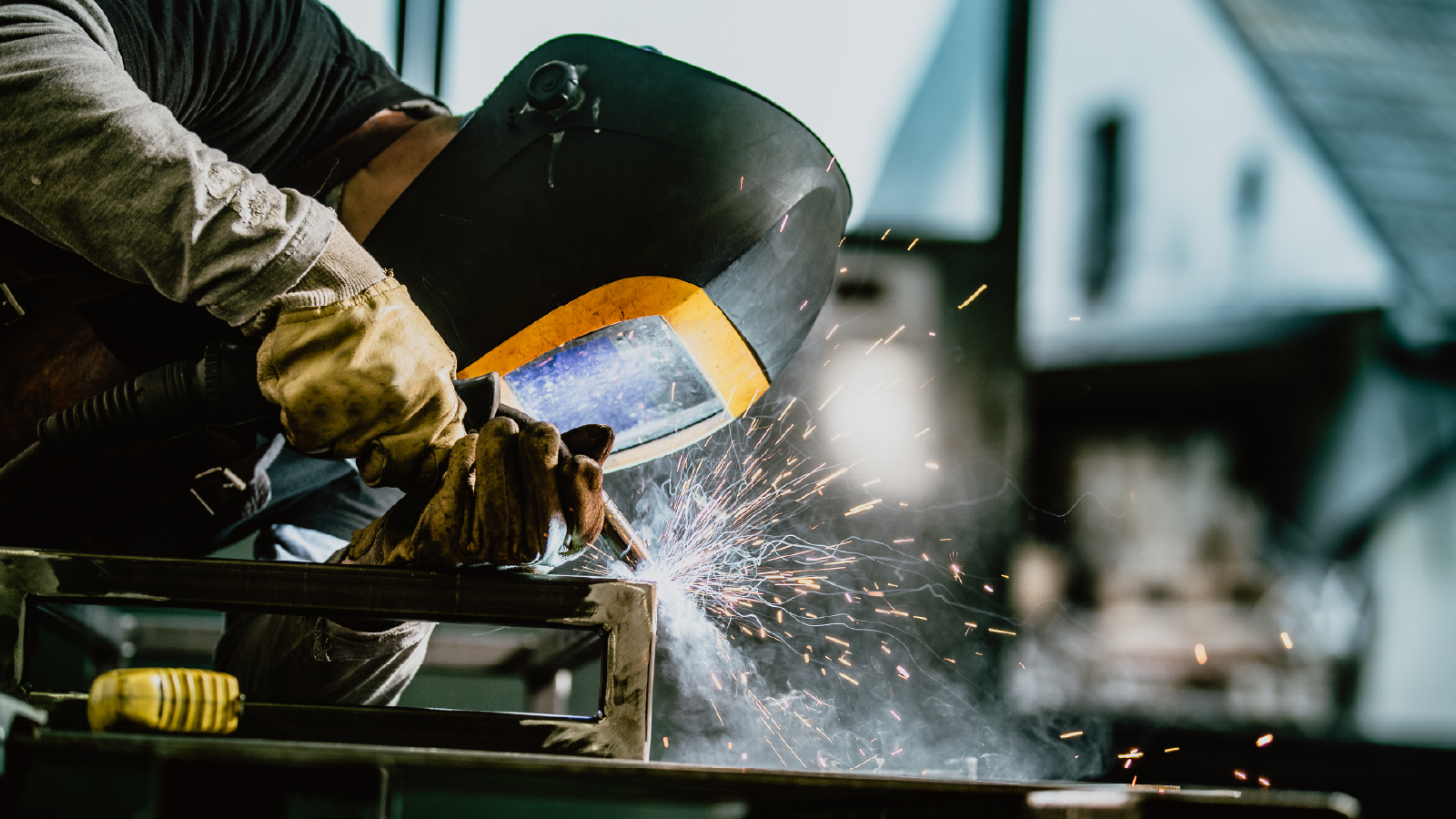 Person wearing protective gear while welding metal