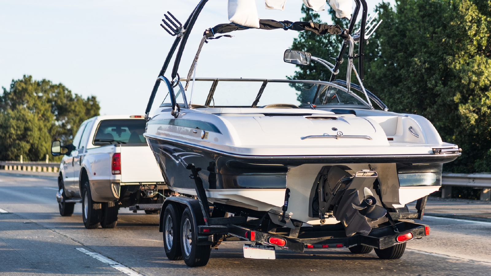 White truck towing boat on scenic highway