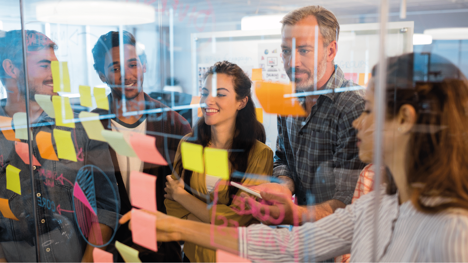 Group of coworkers discussing around a glass whiteboard