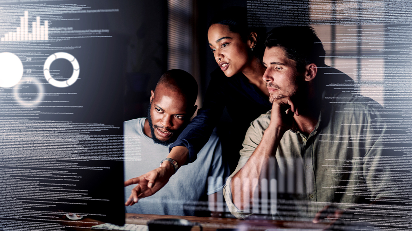 A team of three collaborating in front of a computer screen displaying digital analytics and data visualization.