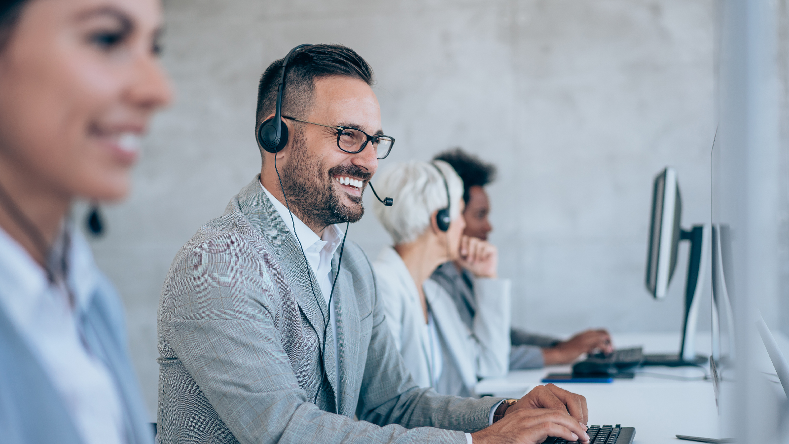 Coworkers at their desks smiling while talking on headsets