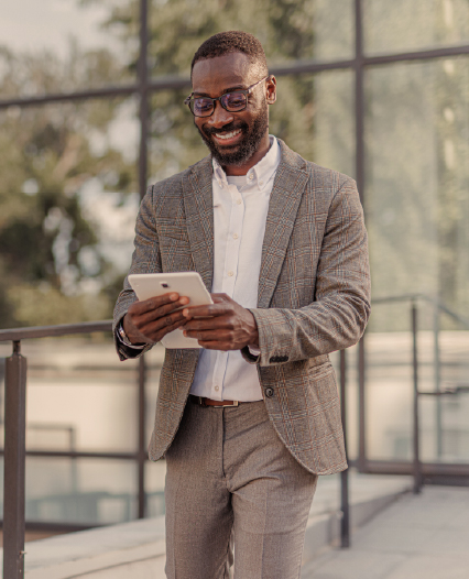 A man in a suit and glasses stands on a sidewalk next to a glass rail, exuding professionalism and confidence.