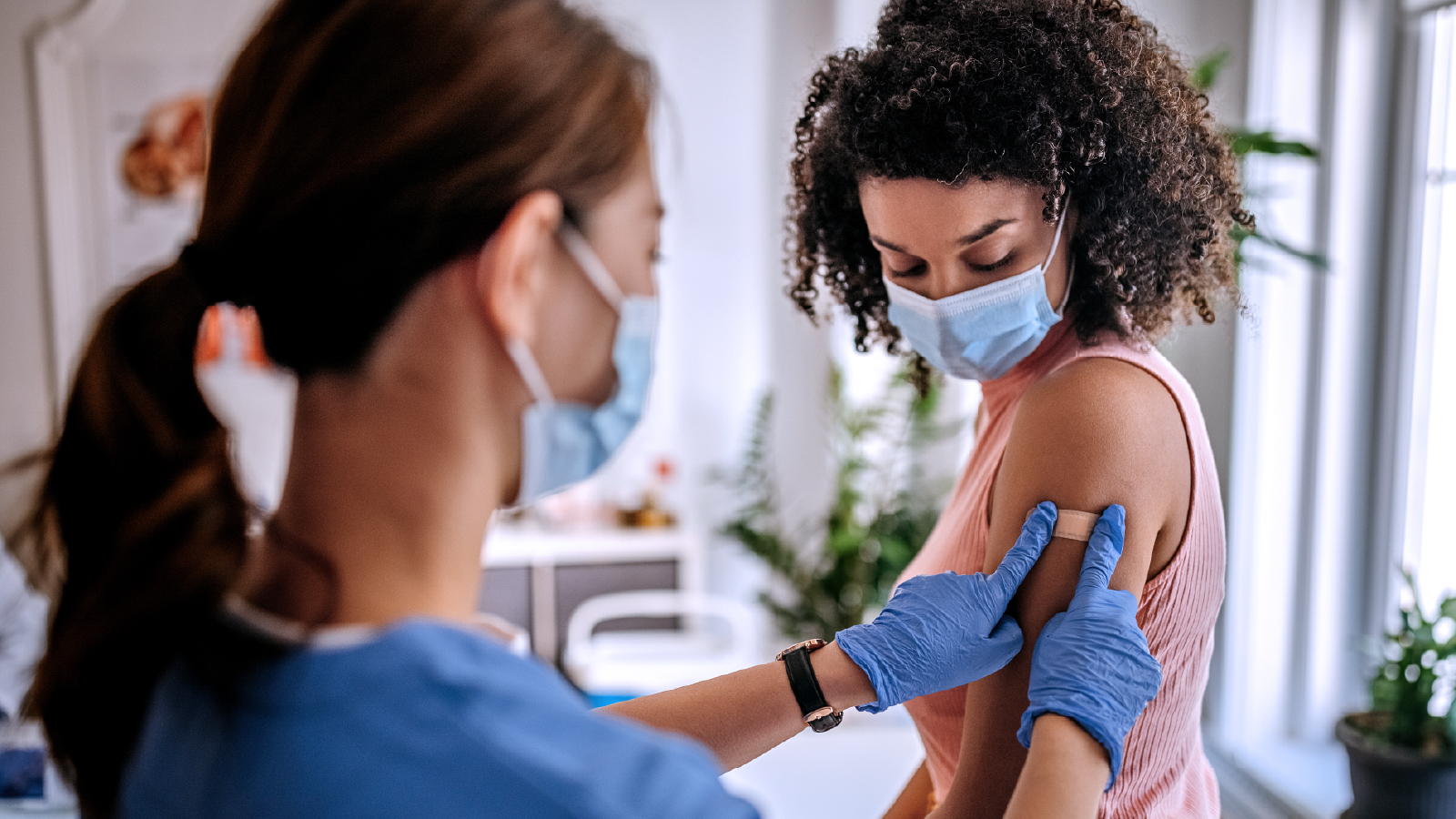 Woman placing a bandaid on a patients arm