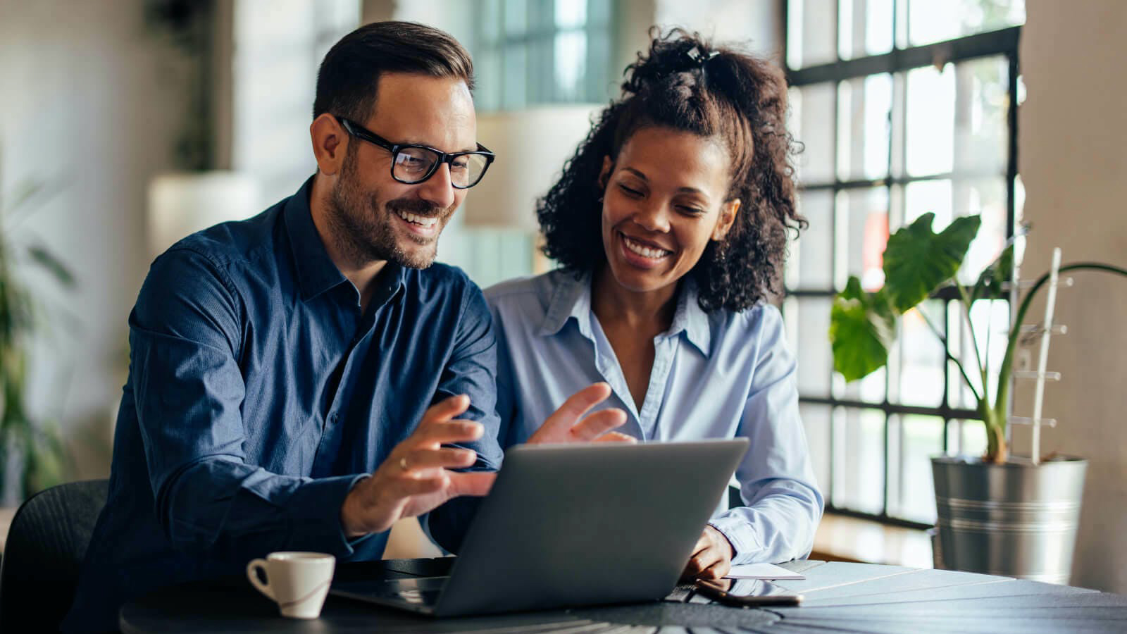 Two coworkers at a desk working on a laptop together