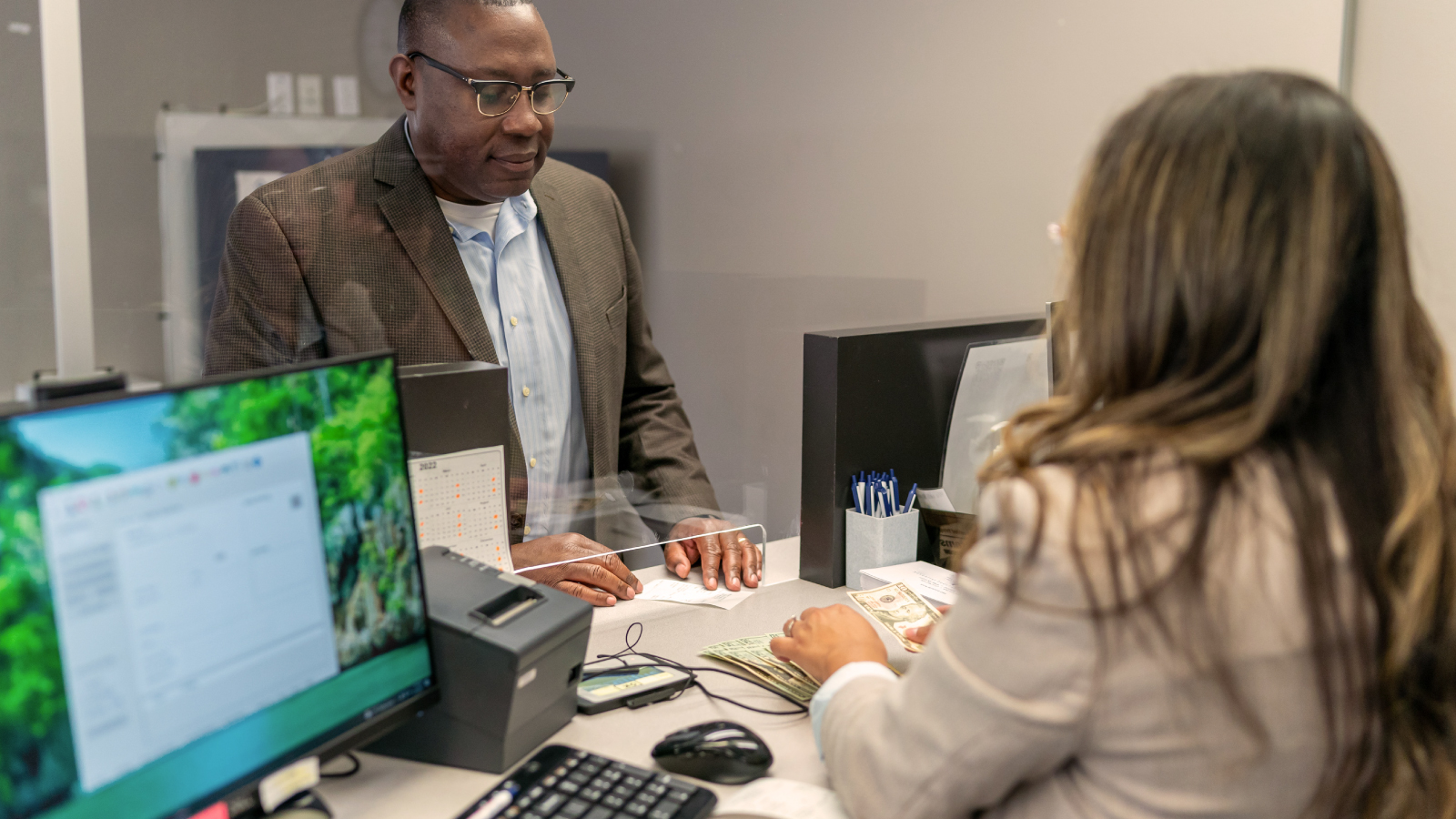 A bank teller serving a man in the bank