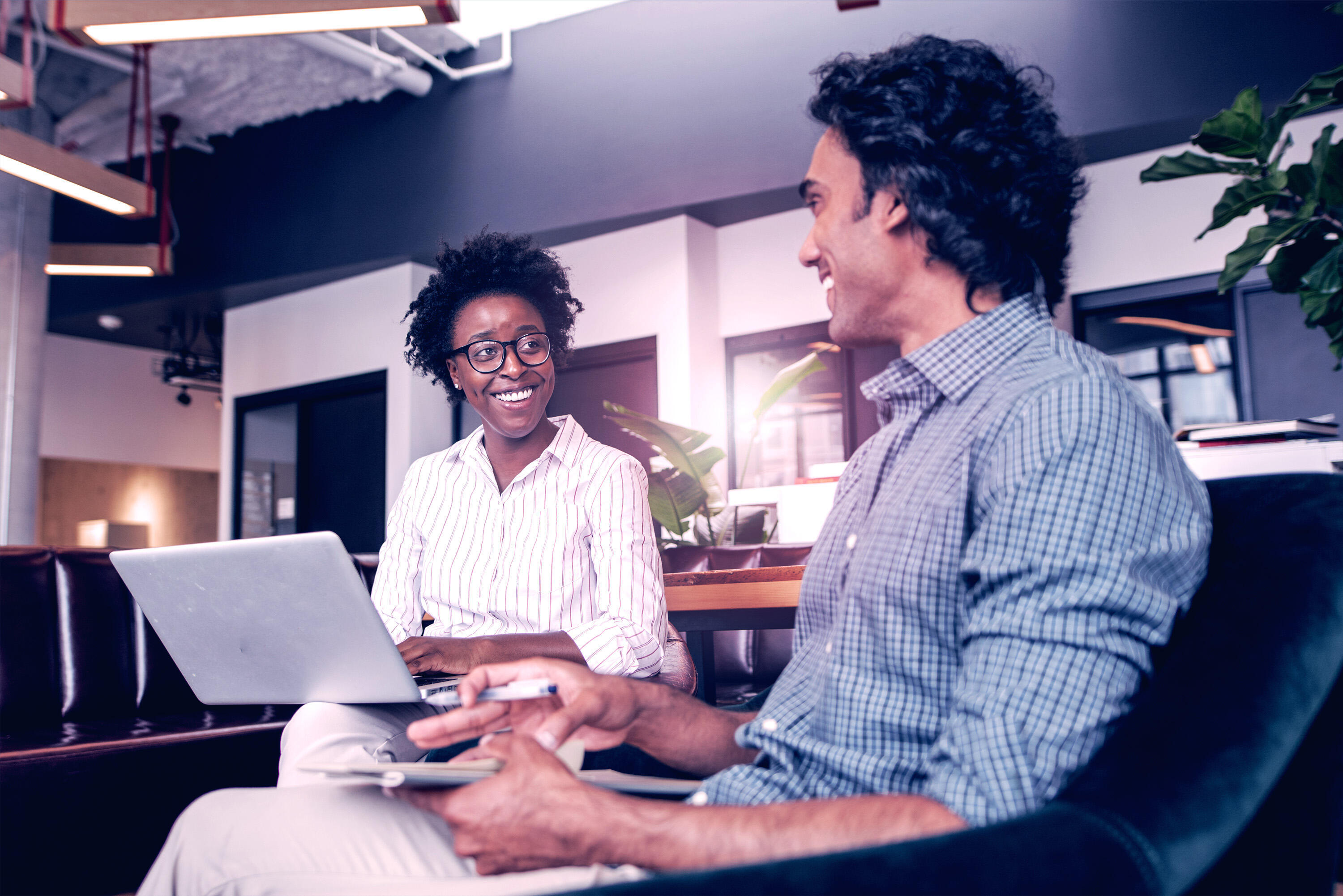 Two coworkers sitting in an office smiling