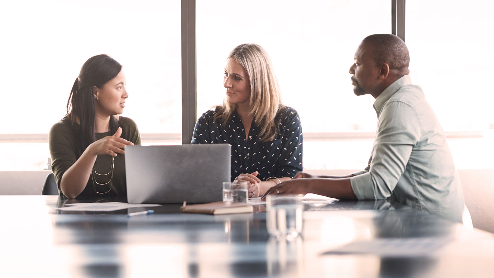 Anaplan white paper on strategic workforce blueprinting for banks. The text highlights workforce optimization and cost-saving strategies, with an image of three professionals in discussion at a conference table.