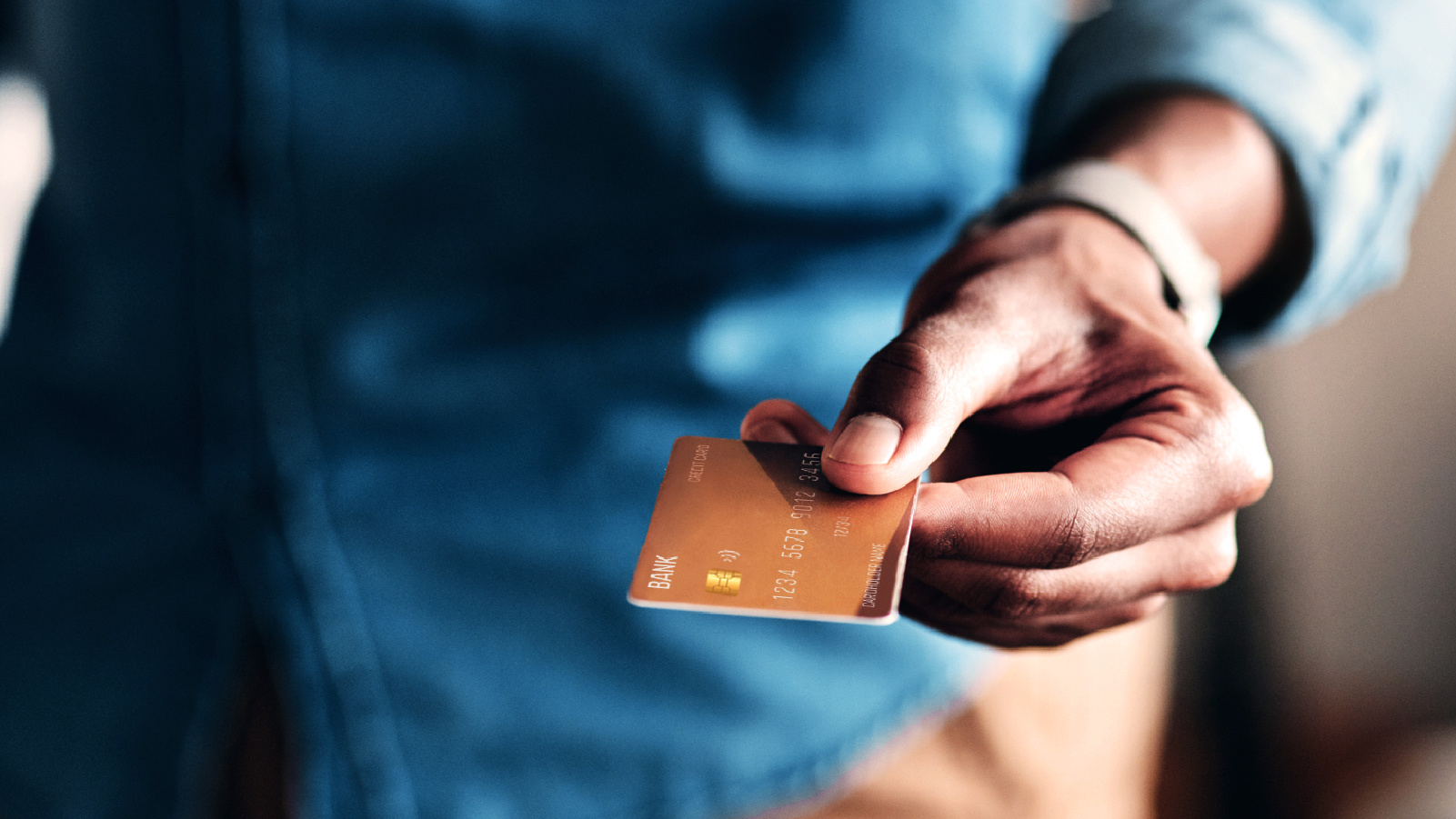 A hand is grasping a credit card, symbolizing financial transactions or shopping activities.