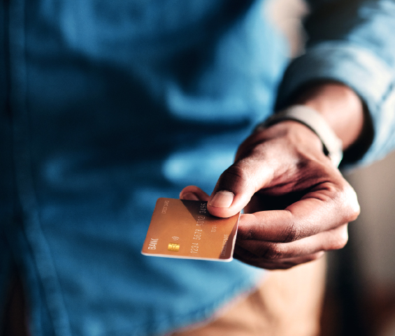 A hand is grasping a credit card, symbolizing financial transactions or shopping activities.