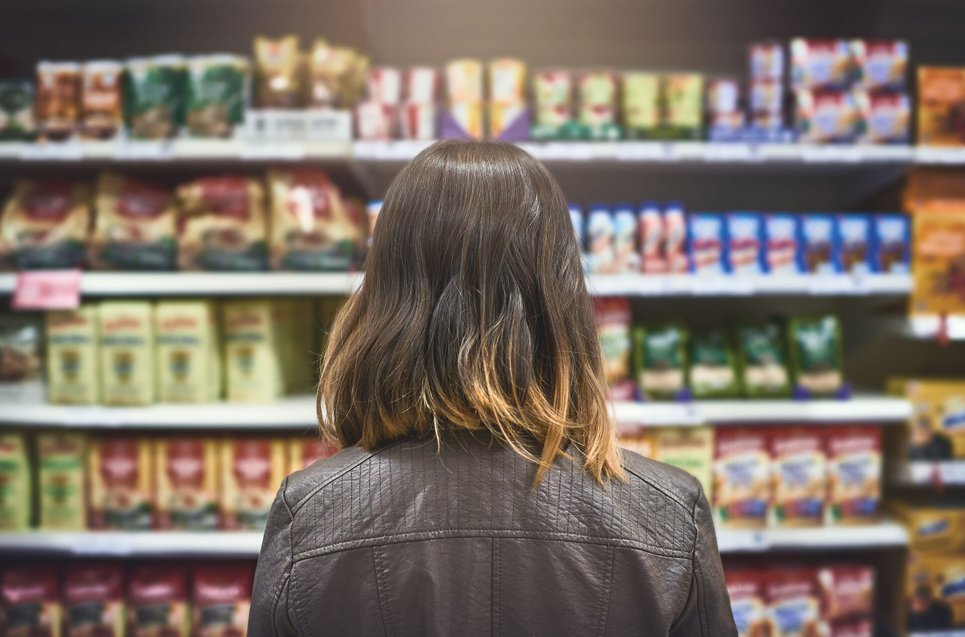 Woman with shoulder-length hair staring at groceries in a grocery store