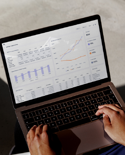 An individual engaged with a laptop, which features a graph, suggesting research or solutions tracking.