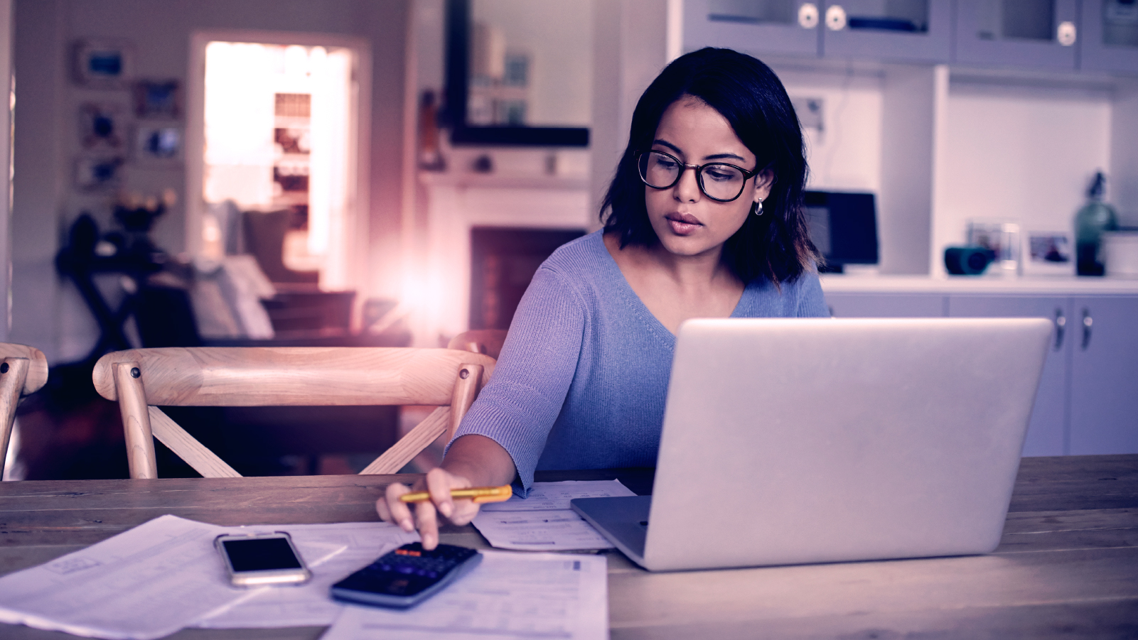 Woman in blue blouse making calculations in home office