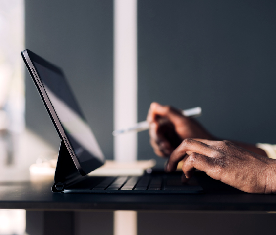 A person focused on typing on a laptop computer, with hands positioned on the keyboard and a screen illuminated.