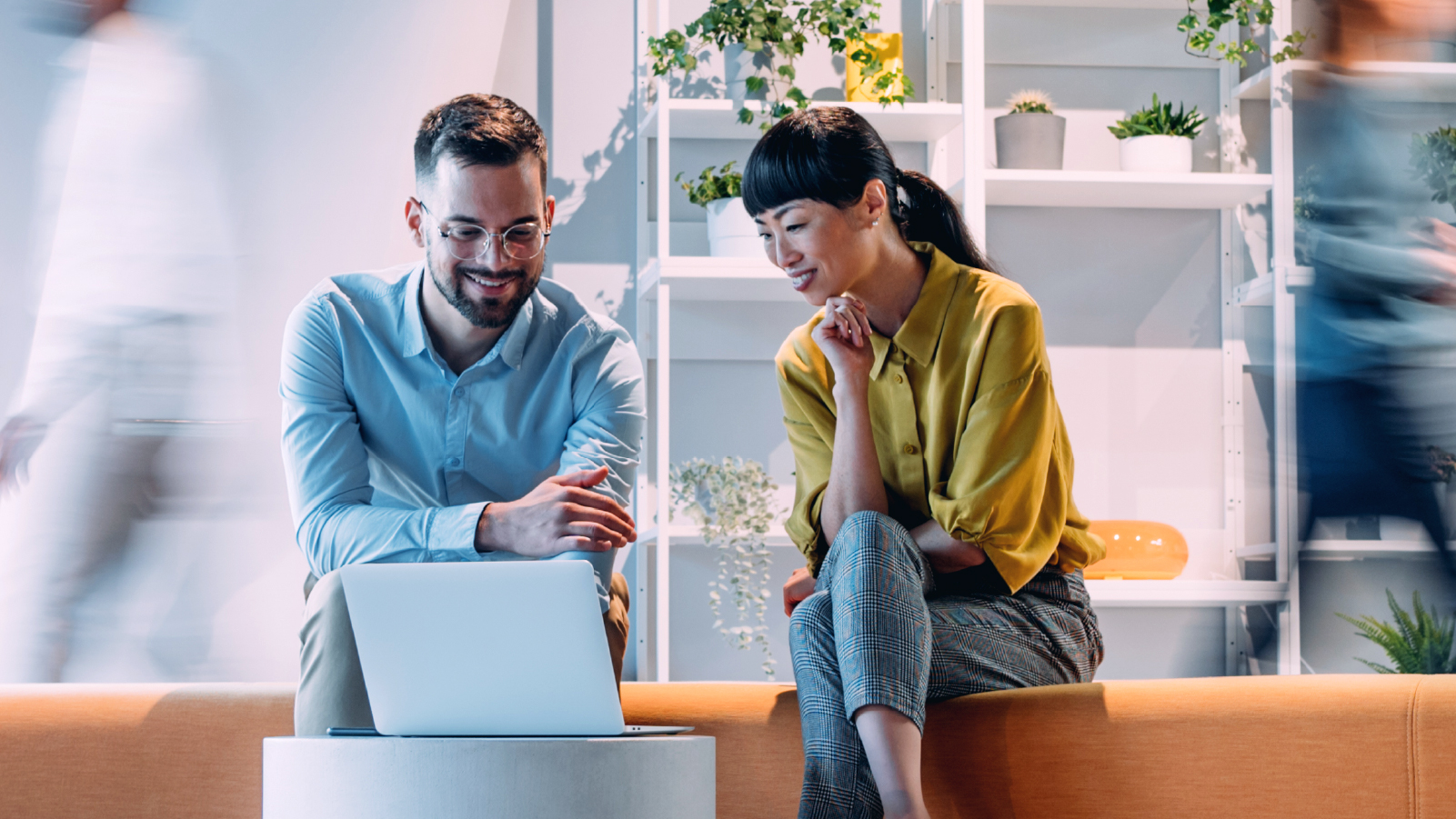 Two individuals seated on a couch, engaged with a laptop in front of them, sharing a moment of collaboration.