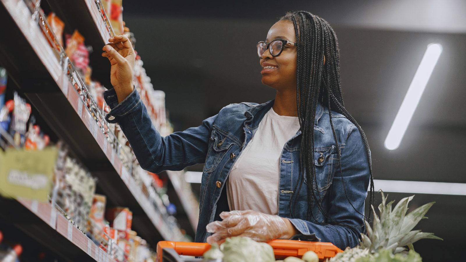 A woman selecting fresh produce in a grocery store aisle, focused on her shopping choices.