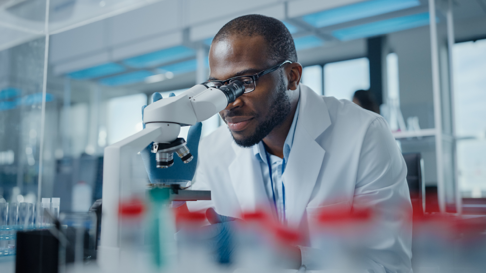 A scientist in a lab coat observes a sample under a microscope, focused on his research in a laboratory environment.