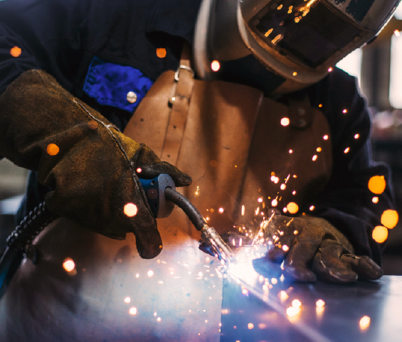 A welder engages in the process of welding metal, surrounded by sparks, demonstrating expertise in fabrication.