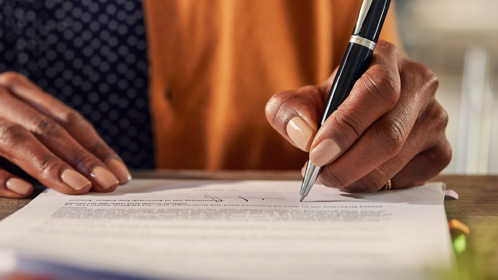 Signing a contract, using a pen to finalize an important document.