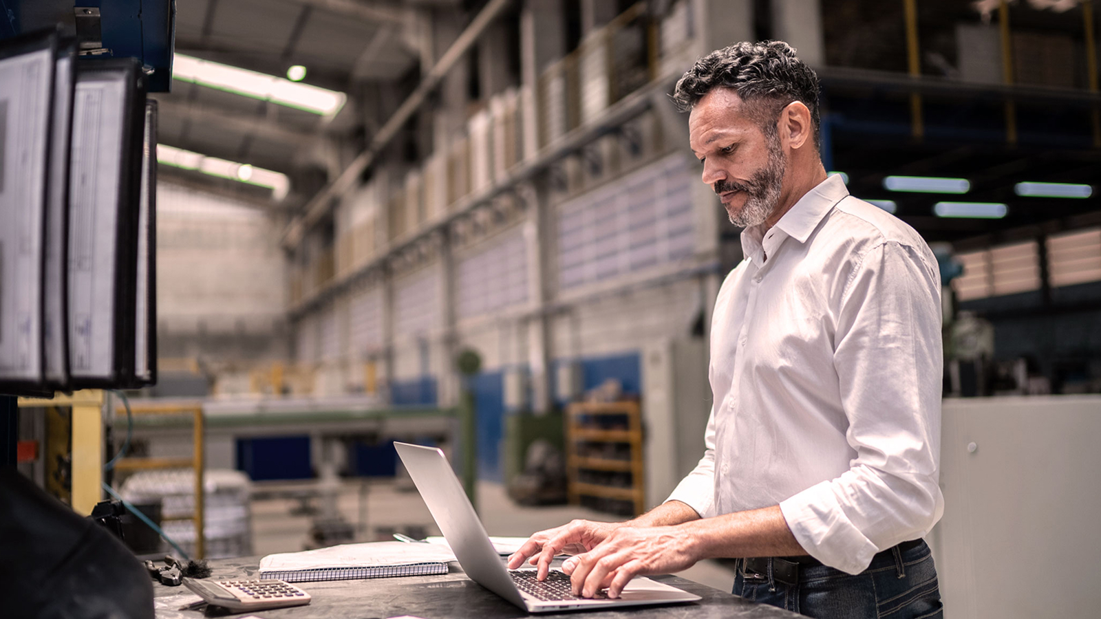 Anaplan eBook on integrated business planning for consumer products manufacturing. The text highlights the shift from concurrent planning to Connected Planning, with an image of an executive managing operations on a laptop in a factory setting.