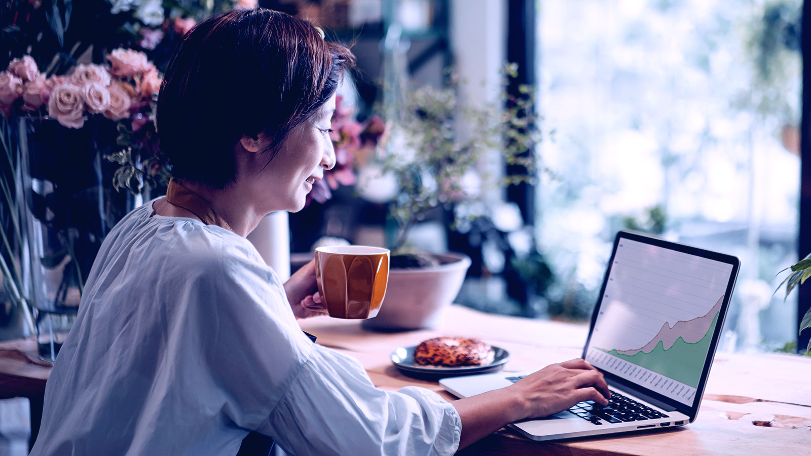 A women smiling while looking at a graph on a laptop.