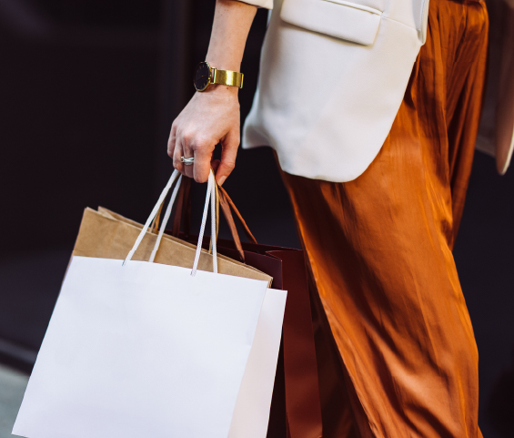 A woman is seen carrying multiple shopping bags in her hands.