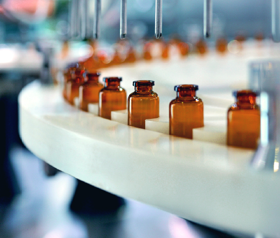 A row of medicine bottles moving along a conveyor belt in a pharmaceutical setting.