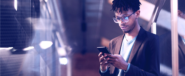 Businessman dressed in a blazer looking at his phone in a warehouse