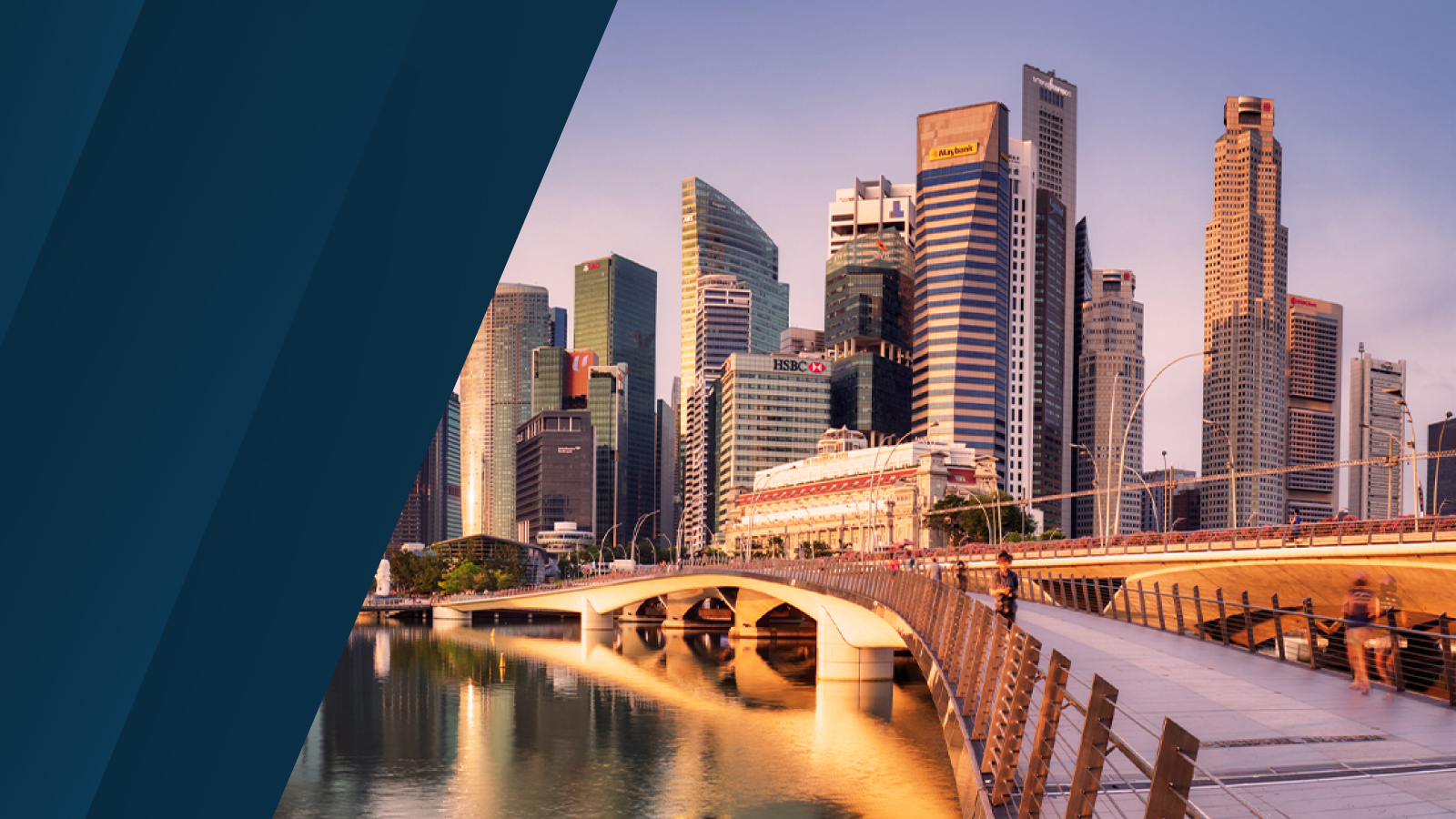 A cityscape of Singapore at sunset, featuring modern skyscrapers and a pedestrian bridge over calm waters.