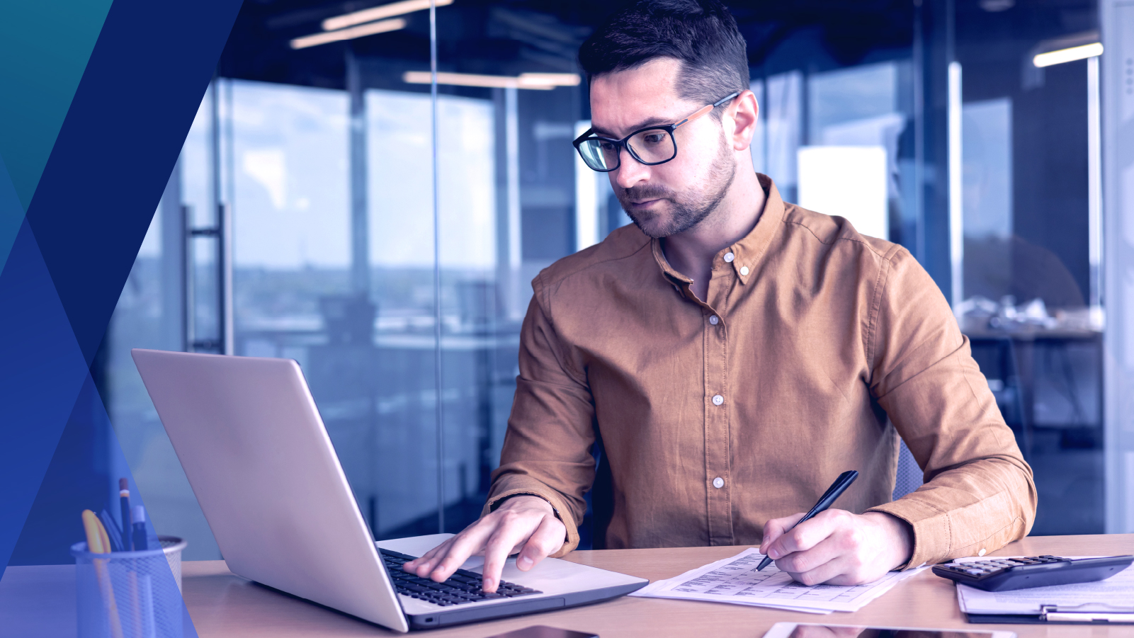  Man working at desk with a laptop and a notebook 